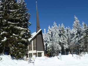 Tiefverschneite Kapelle St Michael-Kapelle mit ihrer dreieckingen Front und spitz zulaufenden hohen Turm