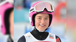 Portrait von strahlender Nathalie Armbruster in Sportkleidung mit lila Uvex-Helm auf dem Kopf.