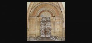 Das zweiflügelige Hauptportal aus massivem Tannenholz beeindruckt mit kunstvollen, schmiedeeisernen Zierbeschlägen. Oben hat die Tür einen halbrunden romanischen Bogen als Abschluss. Vor der Tür stehen links und rechts Halbsäulen, die auf Tür zulaufen