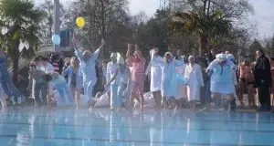 Gruppe von Frauen und Männder die meist mit einem Pyjama bekleidet ins Becken des Karlksruher Freibads springen.