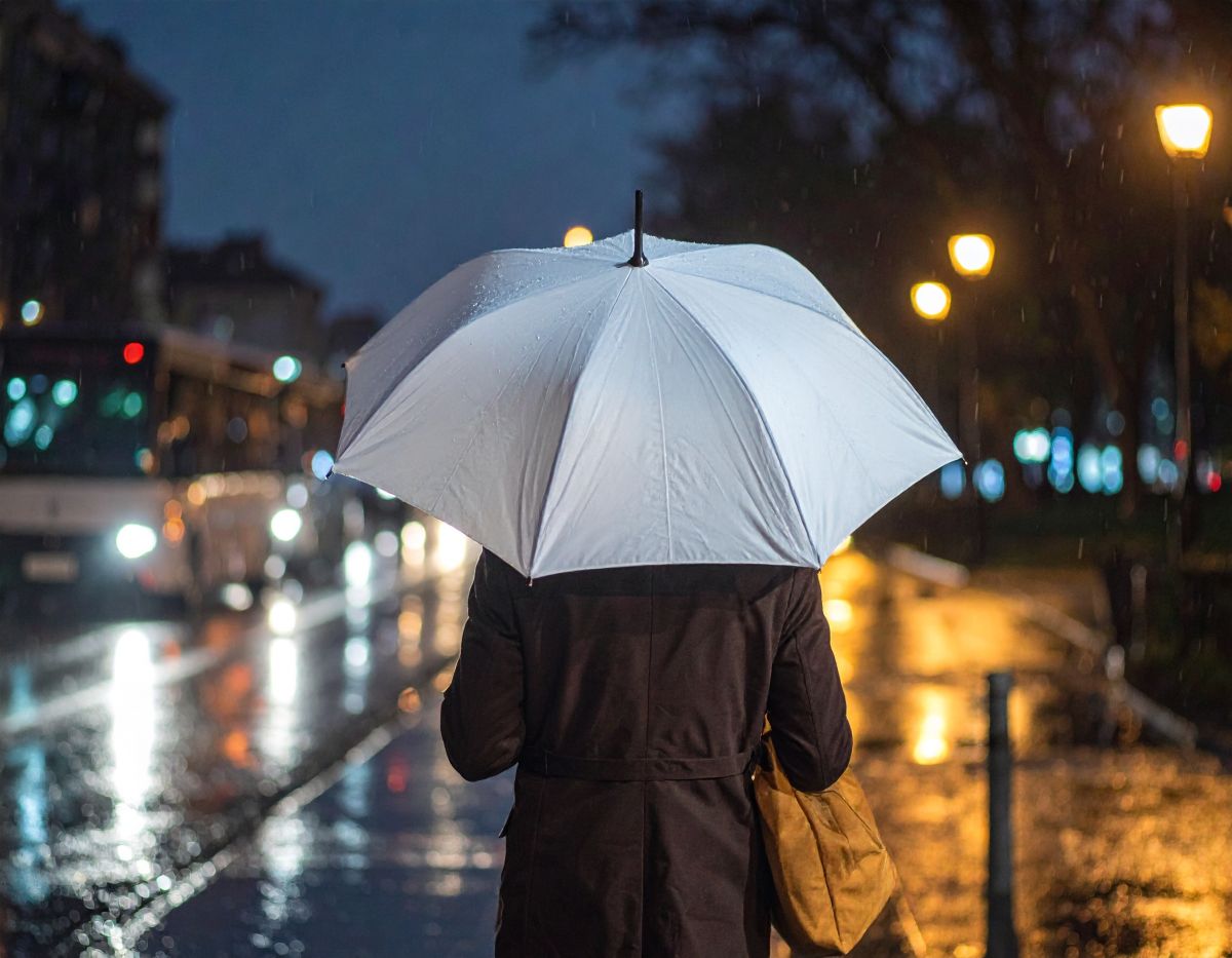 Person mit aufgespanntem Regenschirm in Stadt
